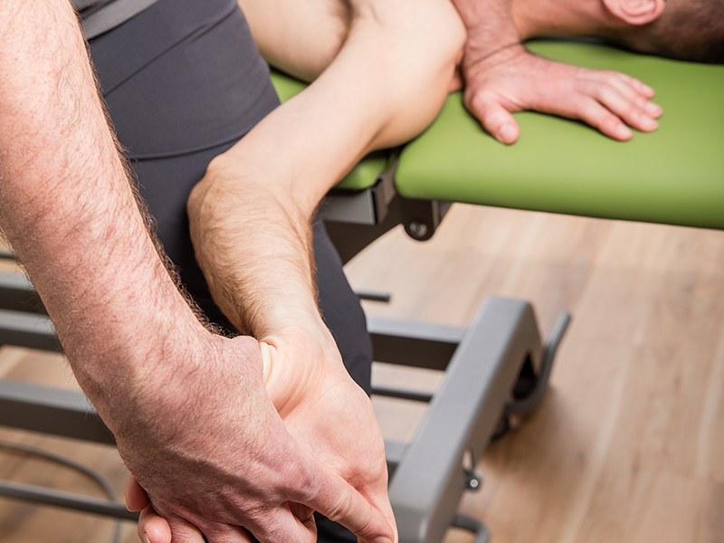 An einer liegenden Patientin testet der Therapeut die Mobilität der Nerven des Armes. Die Mobilisation der Nerven ist ein wichtiger Bestandteil der Manuellen Therapie und Krankengymnastik der Physiopraxis MeyBaum in Bayreuth.